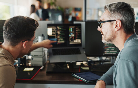 Zwei Softwareentwickler sitzen vor einem Computer