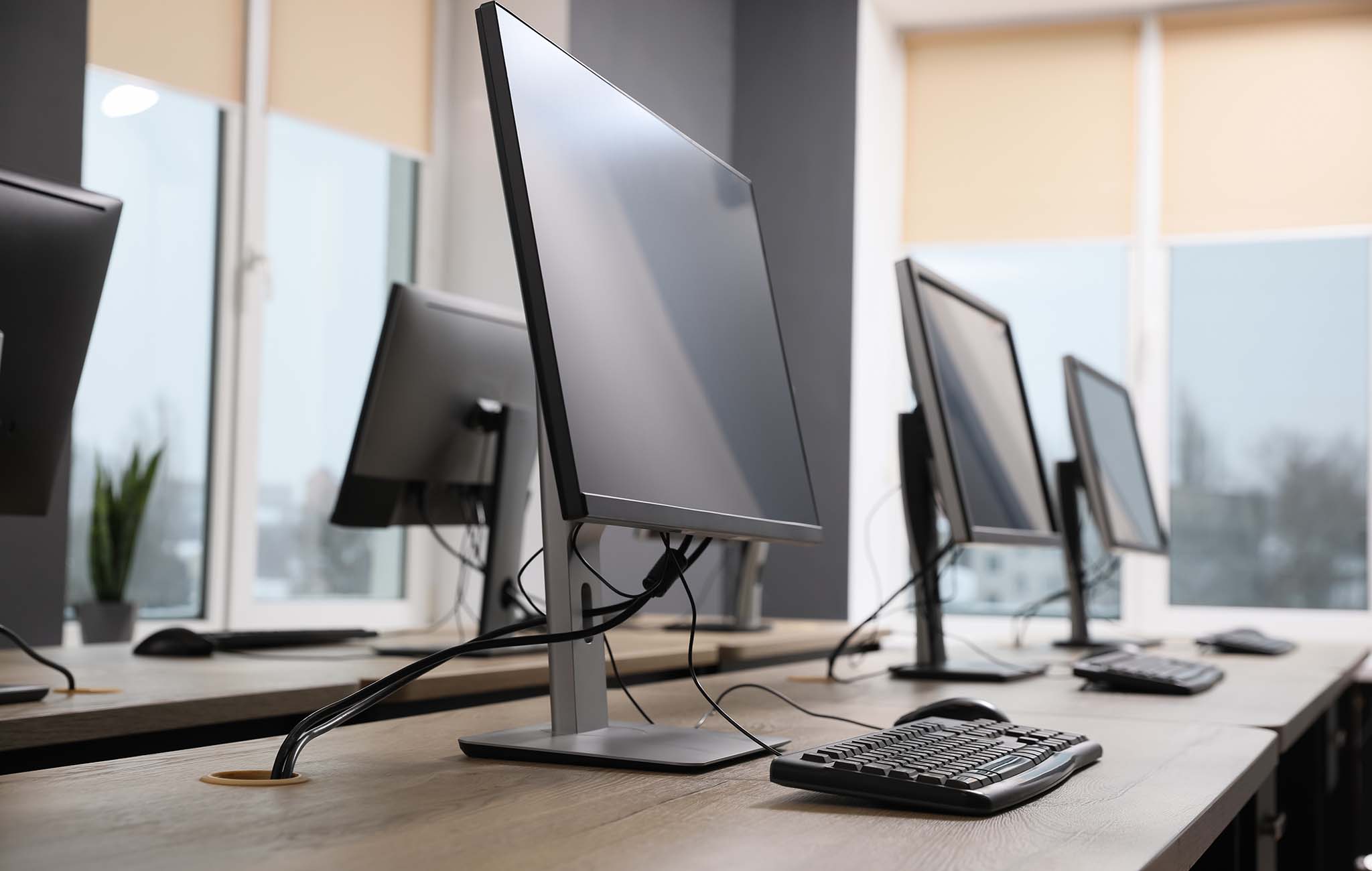 Foto eines modernen Schul-Computerraums mit mehreren Monitoren und Tastaturen auf Schreibtischen, geeignet für den Einsatz von paedML-Systemen.