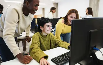 Drei Jugendliche in guter Stimmung, lachend mit Blick in den PC.